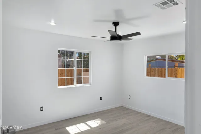 an empty room with wooden floor and windows