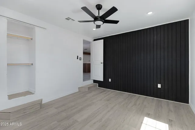 an empty room with wooden floor and a ceiling fan