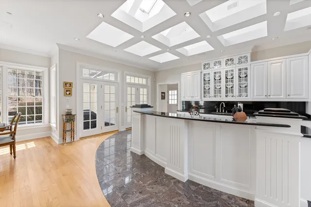 a kitchen with sink and white cabinets with wooden floor