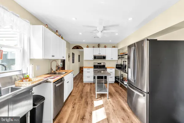 a kitchen with stainless steel appliances a refrigerator a stove a sink dishwasher and a dining table with wooden floor