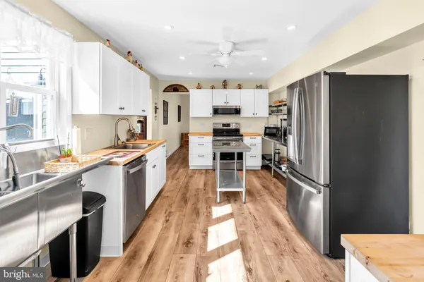 a kitchen with stainless steel appliances granite countertop a stove top oven a sink dishwasher and white cabinets with wooden floor