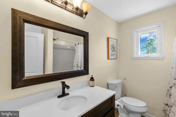a view of a hallway with wooden floor and a bathroom