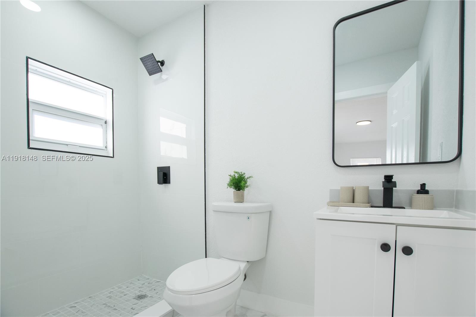 2250 Northwest 95th Terrace Miami, FL 33147 - Photo 9 of 18 a bathroom with a toilet a sink a mirror a vanity and window