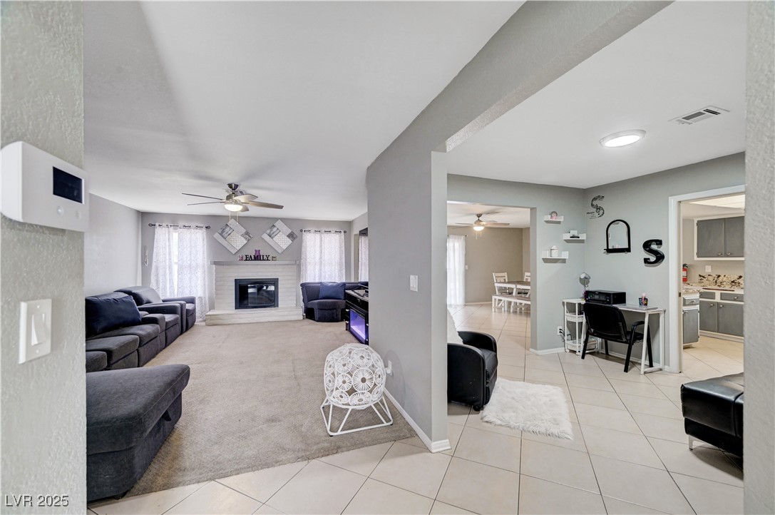 2829 Michael Way Las Vegas, NV 89108 - Photo 15 of 60 Living area with light tile patterned floors, light colored carpet, a glass covered fireplace, and a ceiling fan