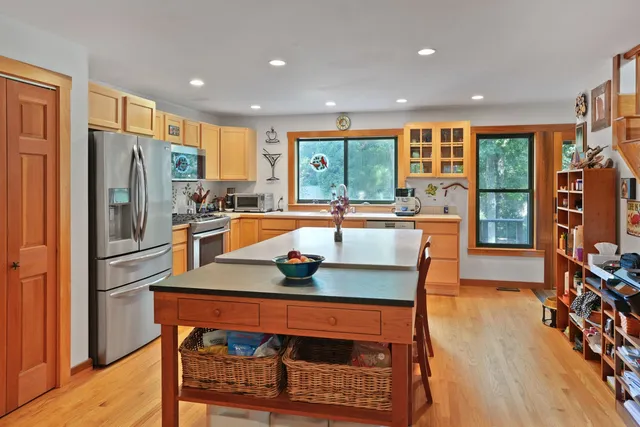 a kitchen with stainless steel appliances granite countertop a refrigerator a stove top oven a dining table and chairs