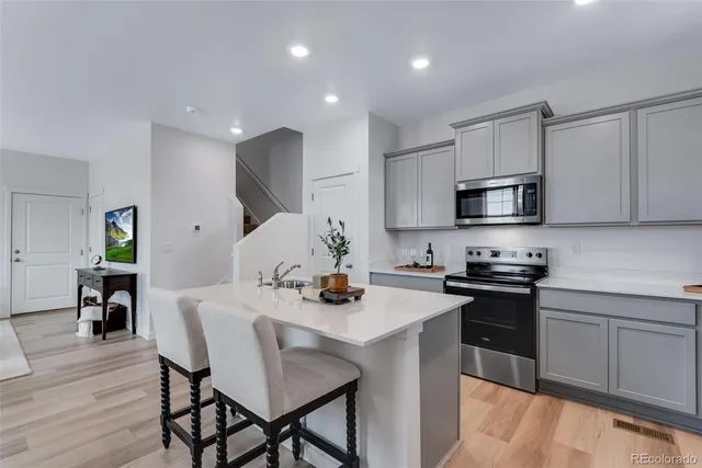 a kitchen with stainless steel appliances granite countertop a stove top oven a sink a stove a dining table and chairs with wooden floor