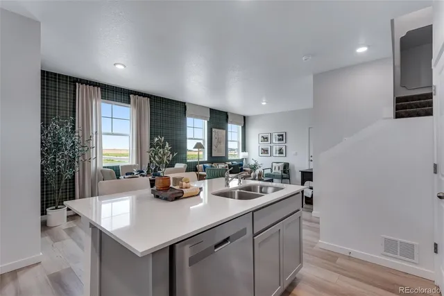 a kitchen with a sink dishwasher and a refrigerator with wooden floor