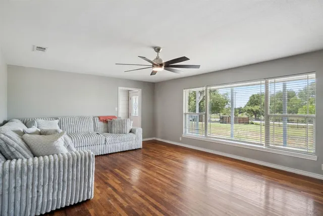 a living room with furniture and a large window with wooden floor