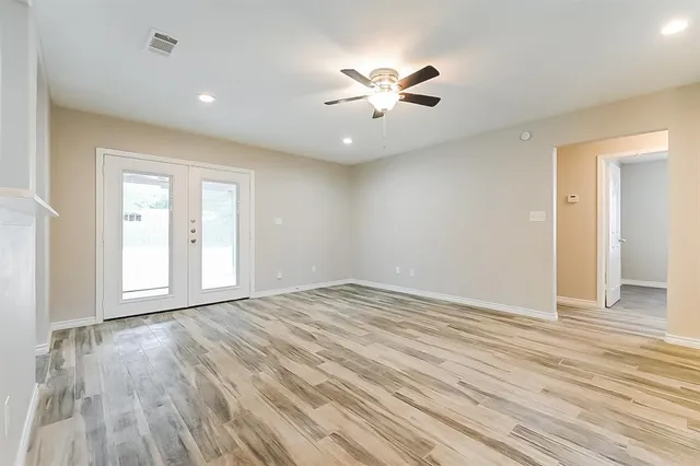 a view of an empty room with wooden floor and window