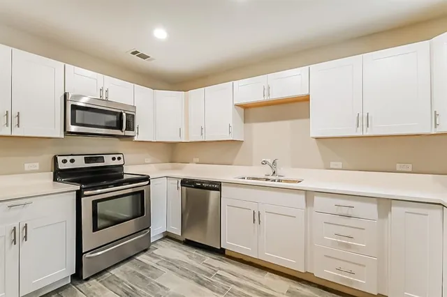 a kitchen with cabinets stainless steel appliances and a sink