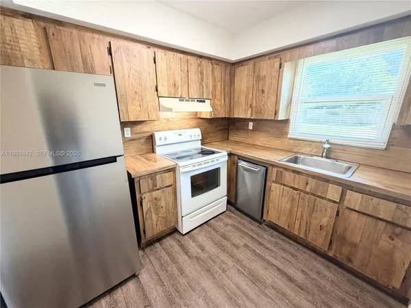 a kitchen with a sink a refrigerator a window and cabinets