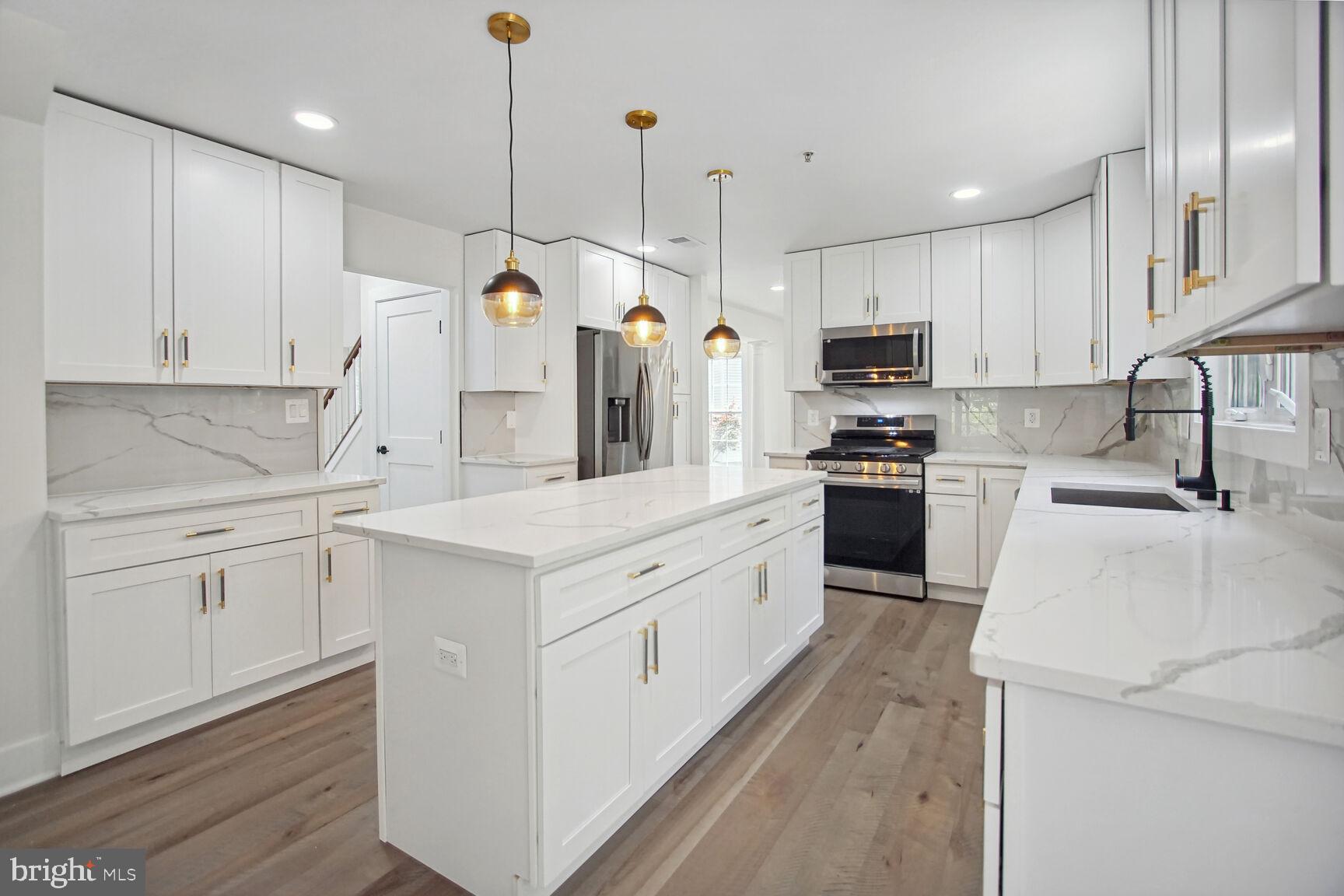 a kitchen that has a lot of white cabinets and stainless steel appliances