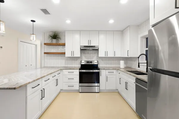 a kitchen with granite countertop white cabinets and stainless steel appliances