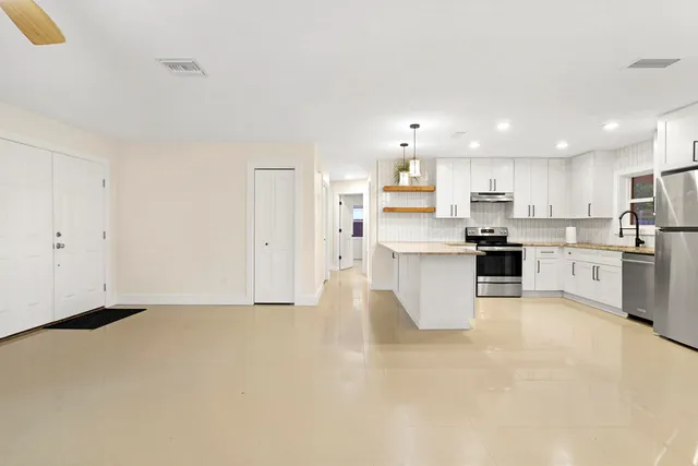 a view of kitchen with kitchen island sink refrigerator and white cabinets