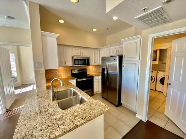 a kitchen with stainless steel appliances granite countertop a refrigerator a stove top oven and sink