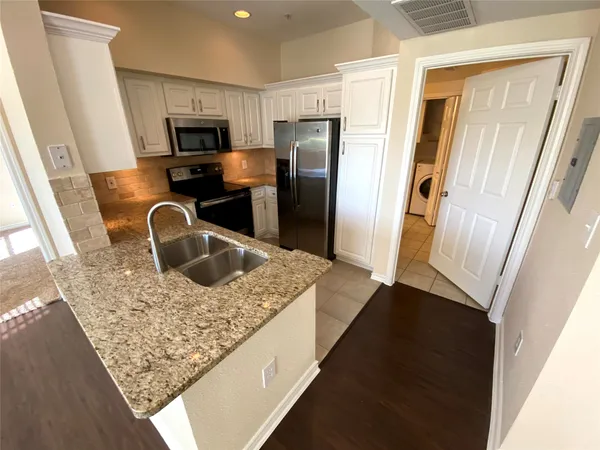 a kitchen with granite countertop a sink a stove and refrigerator