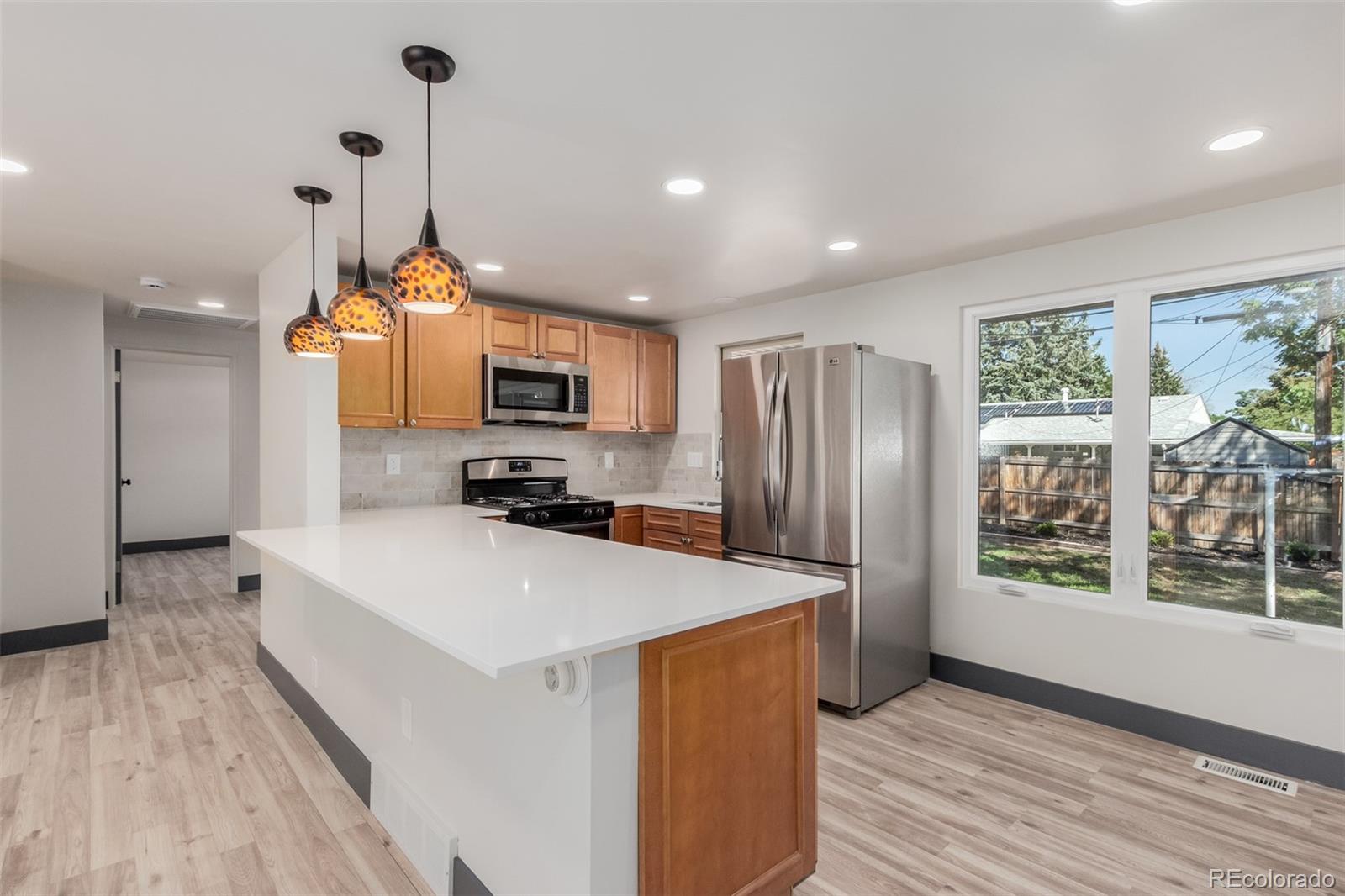 7330 Decatur Street Westminster, CO 80030 - Photo 12 of 37 a large kitchen with sink a refrigerator and wooden floor