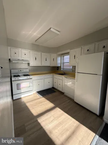 a kitchen with stainless steel appliances granite countertop a refrigerator a stove a sink and white cabinets