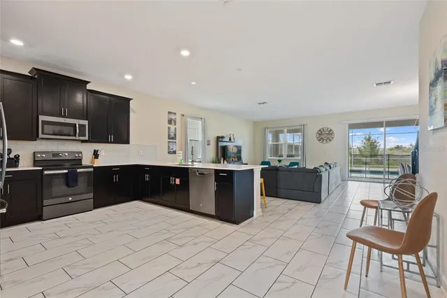 a kitchen with stainless steel appliances kitchen island granite countertop a sink and a refrigerator