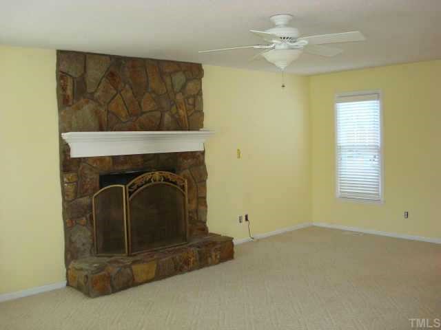 3605 Old Country Lane Raleigh, NC 27616 - Photo 2 of 10 Stone fireplace with gas logs in living room, remote control ceiling fan and berber carpet.