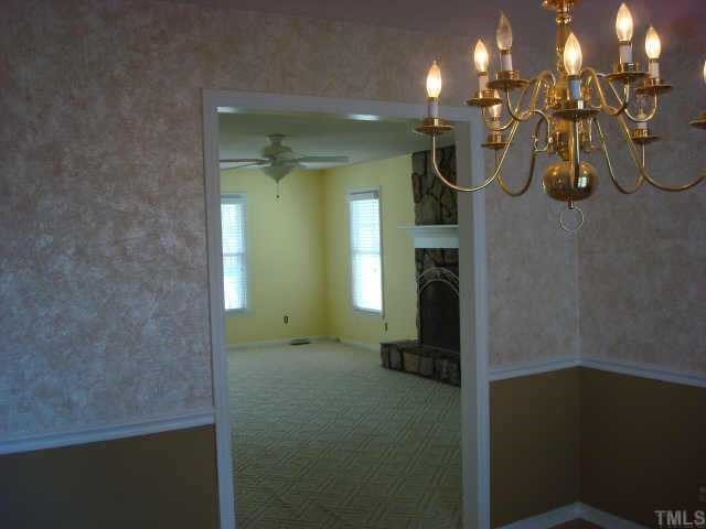 3605 Old Country Lane Raleigh, NC 27616 - Photo 3 of 10 View from dining room into living room. Dining room w/brass chandelier, laminate floors, chair rail, neutral wallpaper.