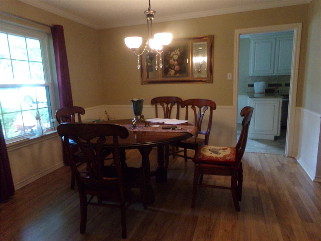 5110 Wedgefield Road Granbury, TX 76049 - Photo 11 of 23 Dining area featuring wood-finish flooring, a double-hung window, crown molding, and wainscoting