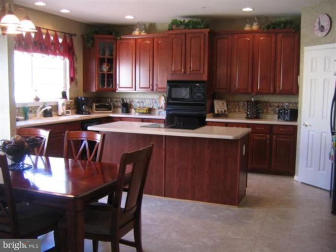 14504 Bubbling Spring Road Boyds, MD 20841 - Photo 13 of 21 a kitchen with a sink a microwave and wooden cabinets