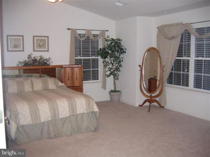 14504 Bubbling Spring Road Boyds, MD 20841 - Photo 3 of 21 a bedroom with a bed a table and potted plants