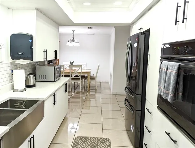 a kitchen with stainless steel appliances a refrigerator a stove a sink a dining table and chairs