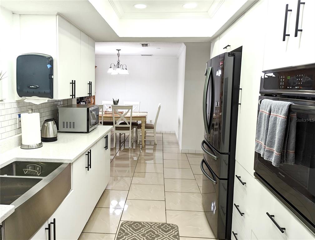 2140 Pinehurst Street Sarasota, FL 34231 - Photo 32 of 40 a kitchen with stainless steel appliances a refrigerator a stove a sink a dining table and chairs