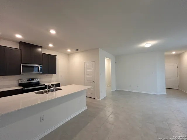 a large kitchen with stainless steel appliances a large counter top a stove a sink a refrigerator and a stove