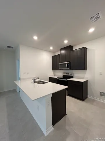 a large kitchen with a large counter top a sink a stove and refrigerator