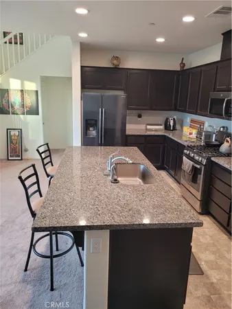 a kitchen with stainless steel appliances granite countertop a sink a stove and a refrigerator