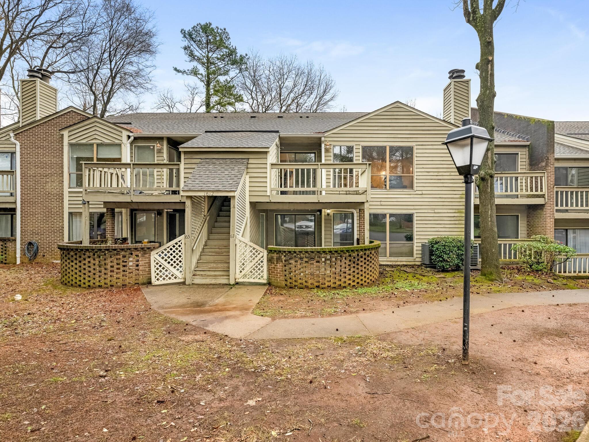 1612 Sharon Road West, Unit 68 Charlotte, NC 28210 - Photo 16 of 18 a view of a white house with large windows next to a road