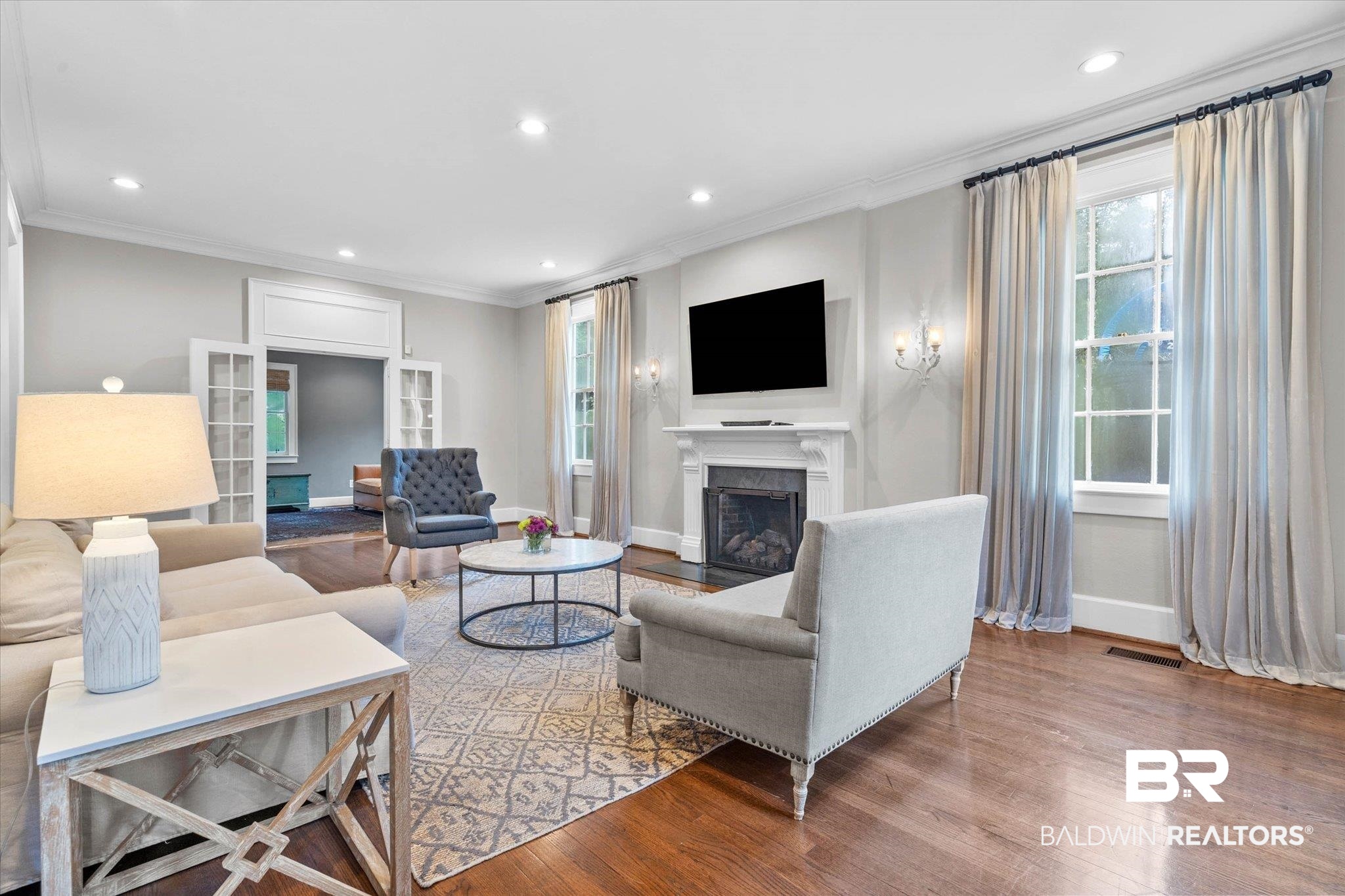 3863 Old Shell Road Mobile, AL 36608 - Photo 3 of 48 Spacious living area featuring rich wood-finish flooring, a white mantel fireplace, recessed lighting, and multiple windows with drapery