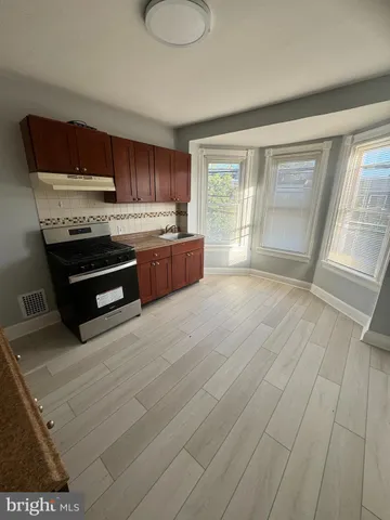 a large kitchen with stainless steel appliances granite countertop a stove a sink and a granite counter tops with wooden floors