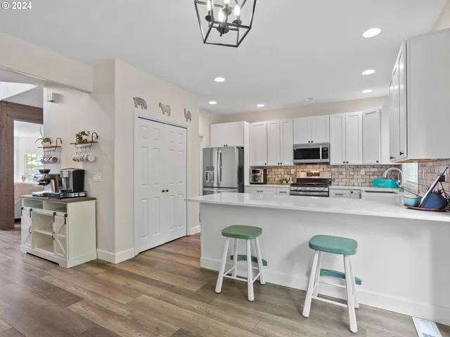 a kitchen with stainless steel appliances granite countertop a table chairs refrigerator and microwave