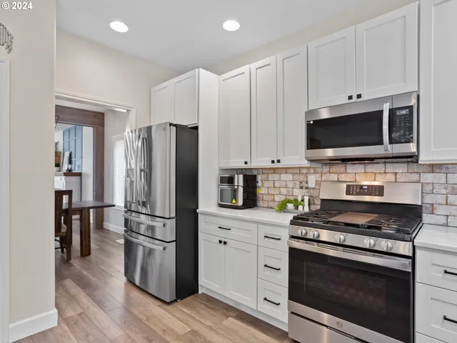a kitchen with cabinets stainless steel appliances and wooden floor