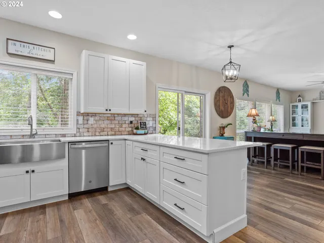 a kitchen with stainless steel appliances kitchen island wooden floors and white cabinets
