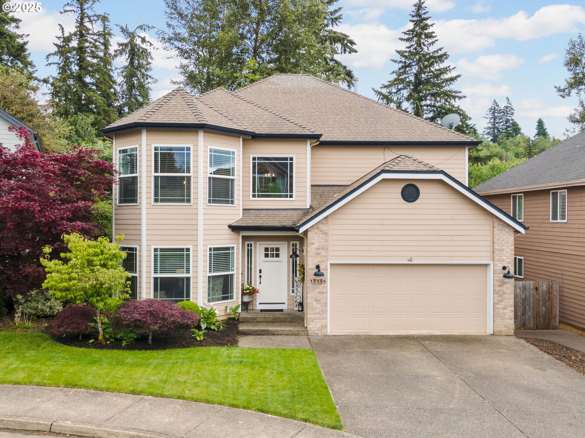 17156 Southeast Macanudo Street Damascus, OR 97089 - Photo 2 of 47 a view of a yard in front of a house with plants and large tree