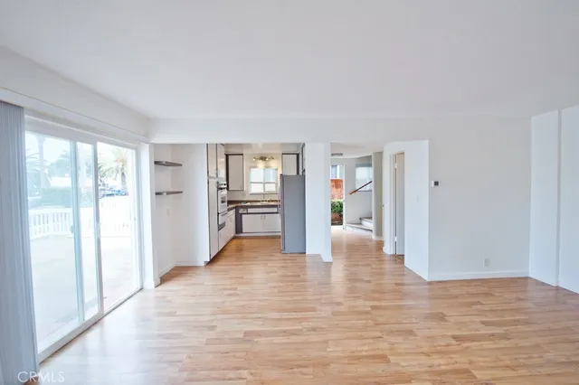 a view of an empty room with window and wooden floor