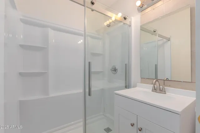 a bathroom with a shower sink vanity and mirror