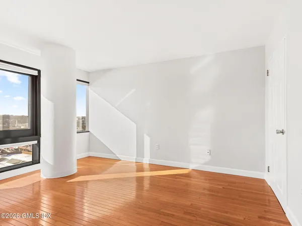 a view of an empty room with wooden floor and a window