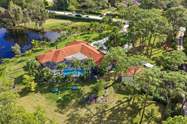 an aerial view of residential house with outdoor space and trees all around