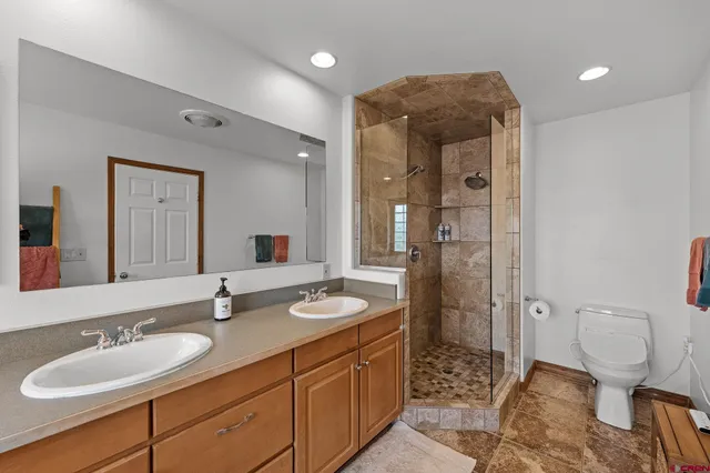 a bathroom with a double vanity sink toilet and shower