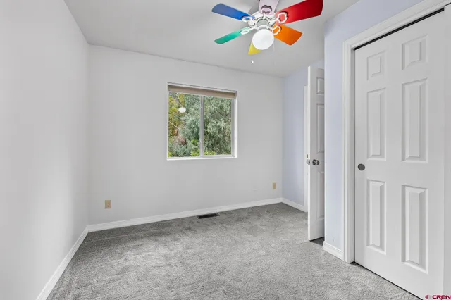 an empty room with windows and ceiling fan
