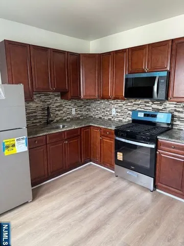 a kitchen with stainless steel appliances granite countertop wooden cabinets a stove top oven a sink and dishwasher