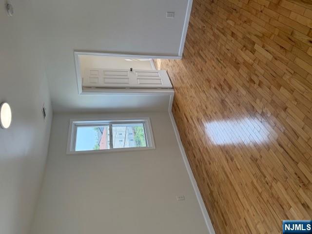 611 South 19th Street, Unit 2 Newark, NJ 07103 - Photo 4 of 8 a view of an empty room with wooden floor and a window