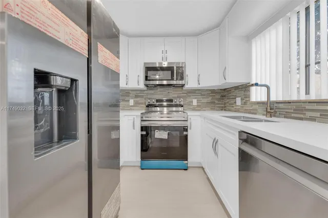 a kitchen with stainless steel appliances granite countertop a stove a sink and a refrigerator