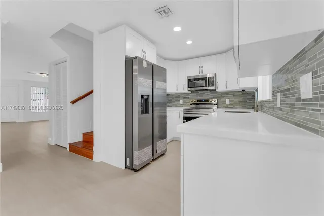 a kitchen with stainless steel appliances granite countertop a refrigerator stove top oven a sink and dishwasher